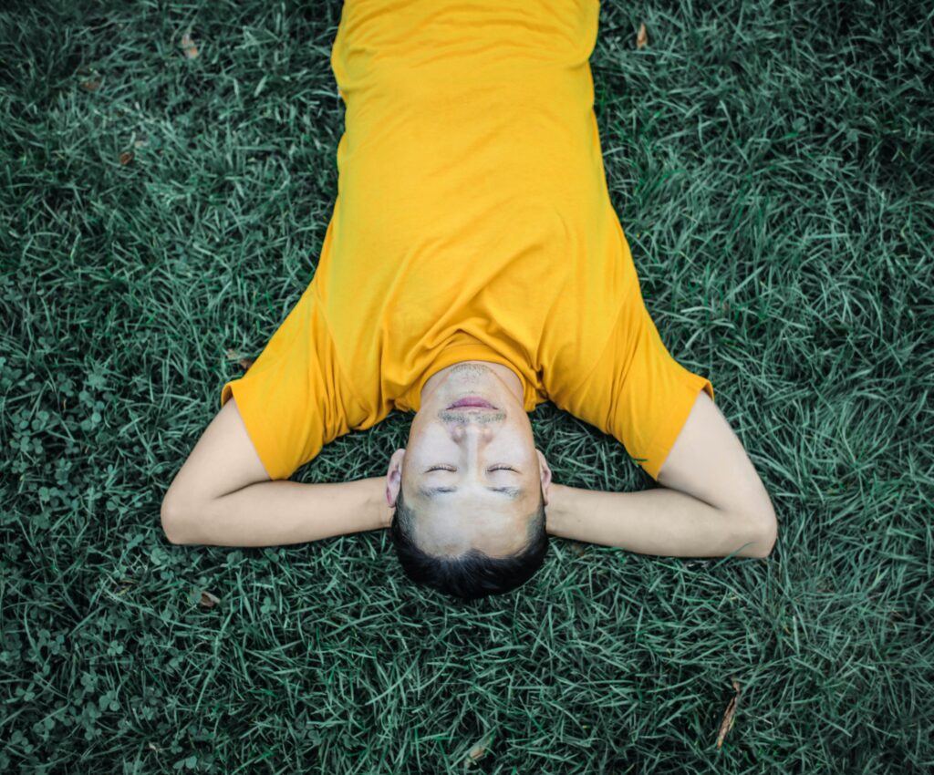 Man laying in grass with eyes closed